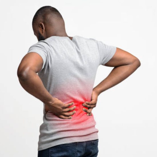 Afro guy holding both hands on lower back, pain in spine, inflamed zone highlighted in red, white background, free space